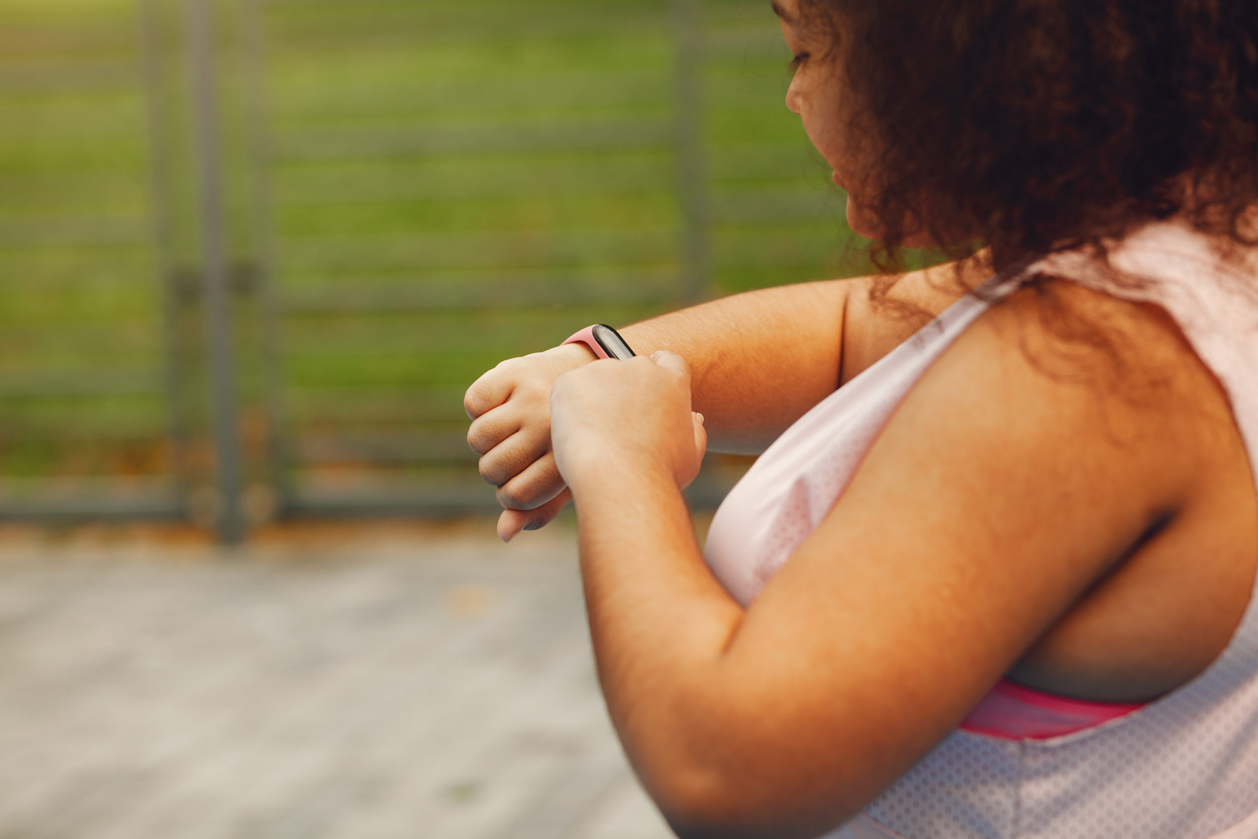 Young tired plus size woman. Girl training in a park. Woman with fithess tracker.