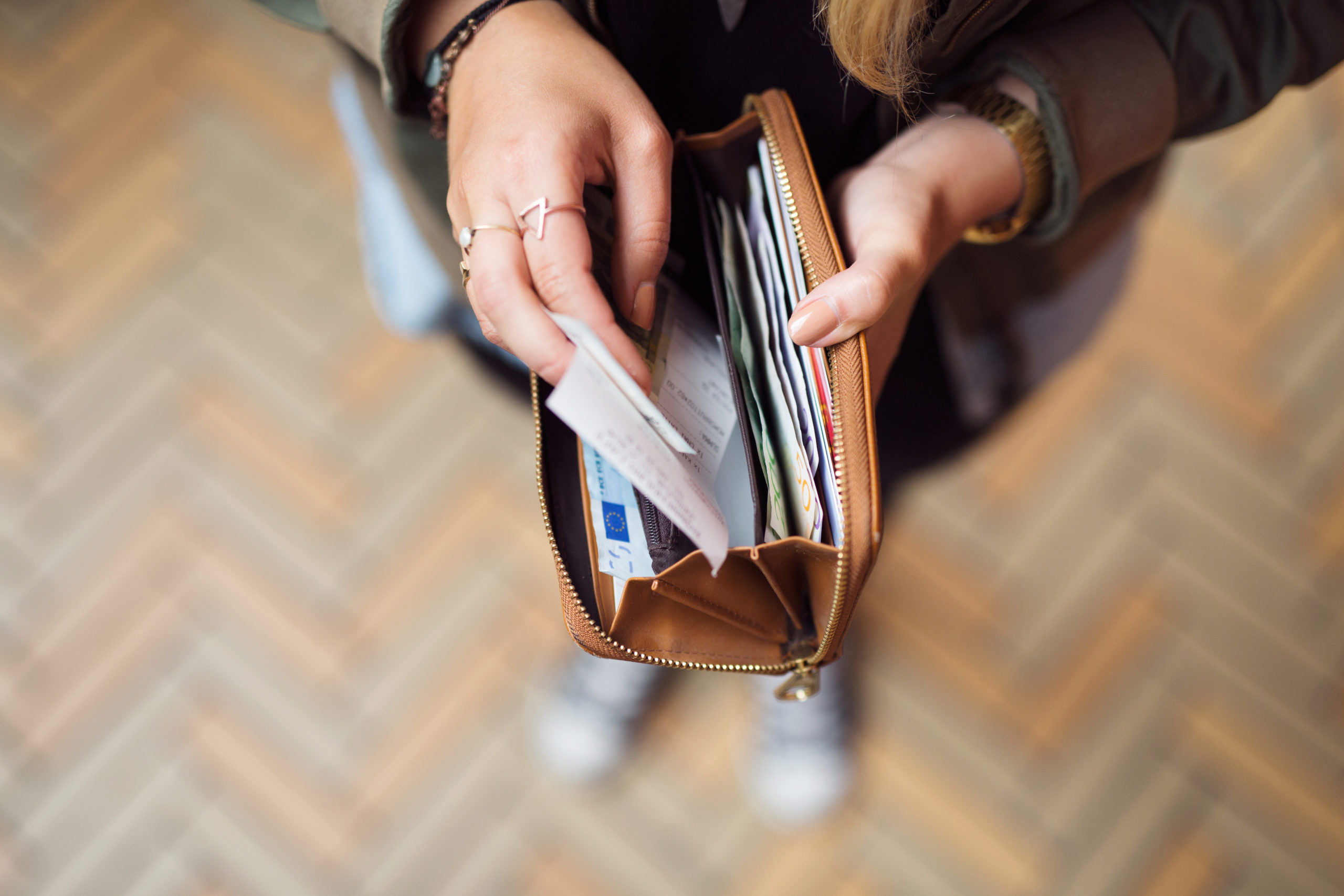 Woman holding open wallet with banknotes and receipts