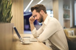 a man sitting at a desk suffering from headaches