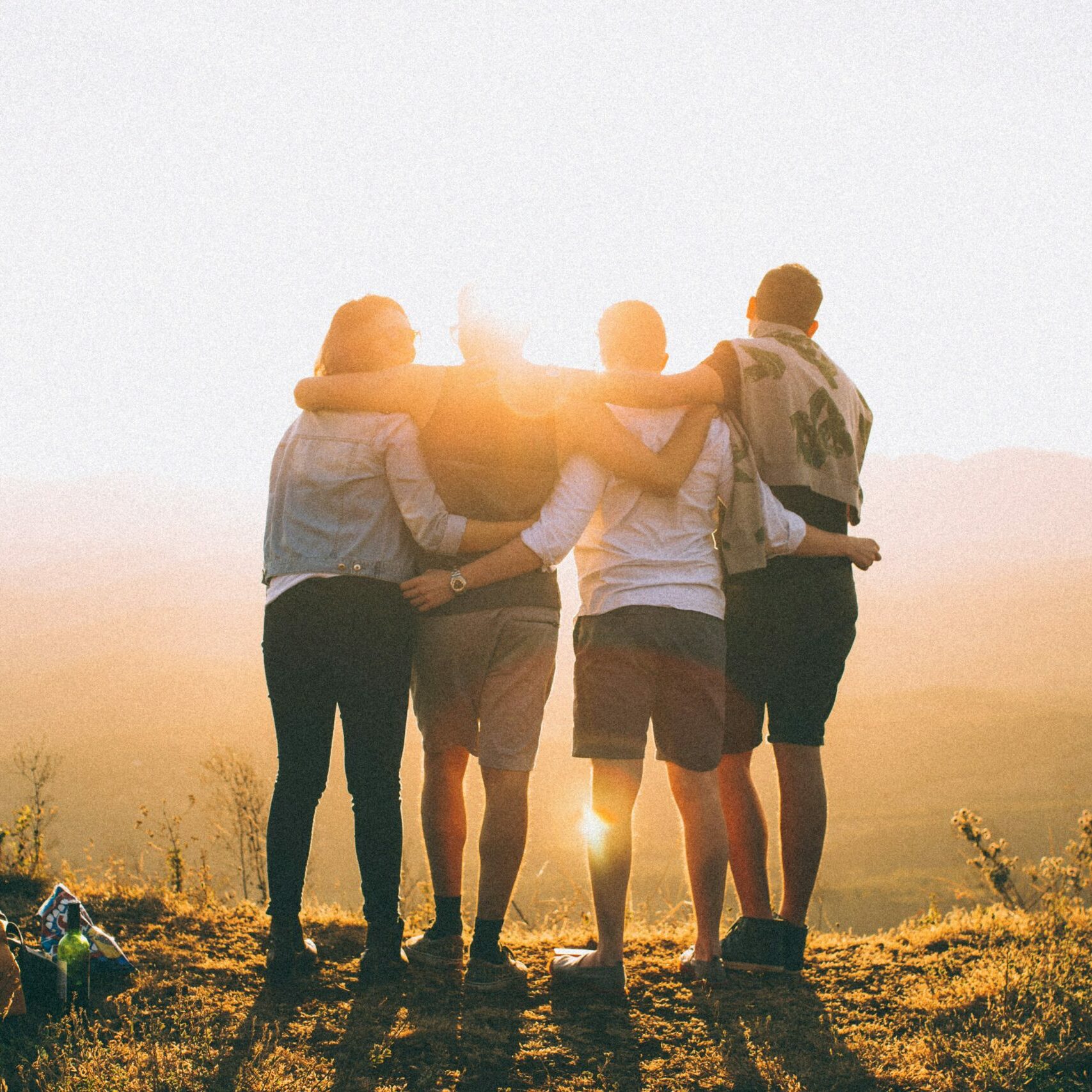 A group of people supporting and caring for each other in front of a sunset.